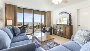 A living room with a large window, a ceiling fan, and a view of the ocean. - Seaside Beach 5417- Two Bedrooms Waterfront Condo With Pool Sauna Amazing Ocean View Balcony (Orange Beach)