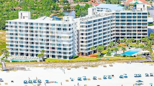A beachfront hotel with multiple floors, a pool, and beach umbrellas. - Seaside Beach 5417- Two Bedrooms Waterfront Condo With Pool Sauna Amazing Ocean View Balcony (Orange Beach)