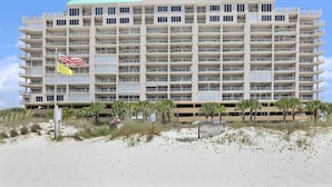 A multi-story hotel with balconies, located near a beach with palm trees. - Regency Isle 1102 3 3 2 Covered Parking Spots Penthouse (Orange Beach)