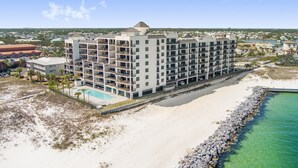 Un hotel a più piani con balconi, piscina e vista sulla spiaggia.