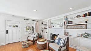 A spacious living room with hardwood flooring, a fireplace, and a bookshelf filled with books and decorative items. - Luxurious Seaside Escape-85 Steps to the Beach-Panoramic Ocean Views (Laguna Beach)
