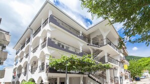 A multi-story building with balconies, a staircase, and a parking area. - Perfect Budva Stay Near the Sea & Aqua Park - Studio with Terrace 1/2 (Budva)