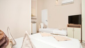 A hotel room with a bed, a TV, a wardrobe, and a small kitchenette. - Perfect Budva Stay Near the Sea & Aqua Park - Studio with Terrace 1/2 (Budva)