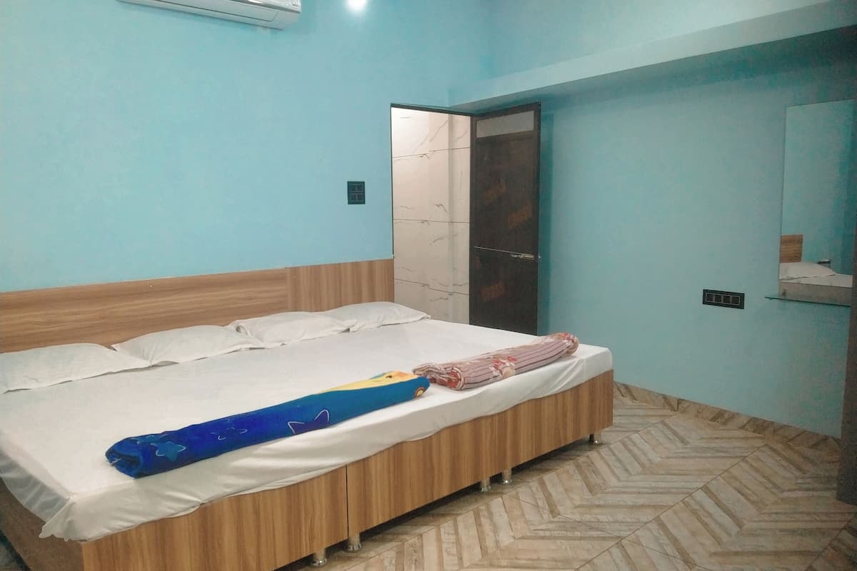 Une chambre avec un lit en bois, un mur bleu et un parquet à motifs en chevrons.