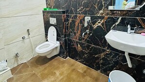 A bathroom with a toilet, sink, shower, and a bucket. - Shreeram guest house (Ujjain)