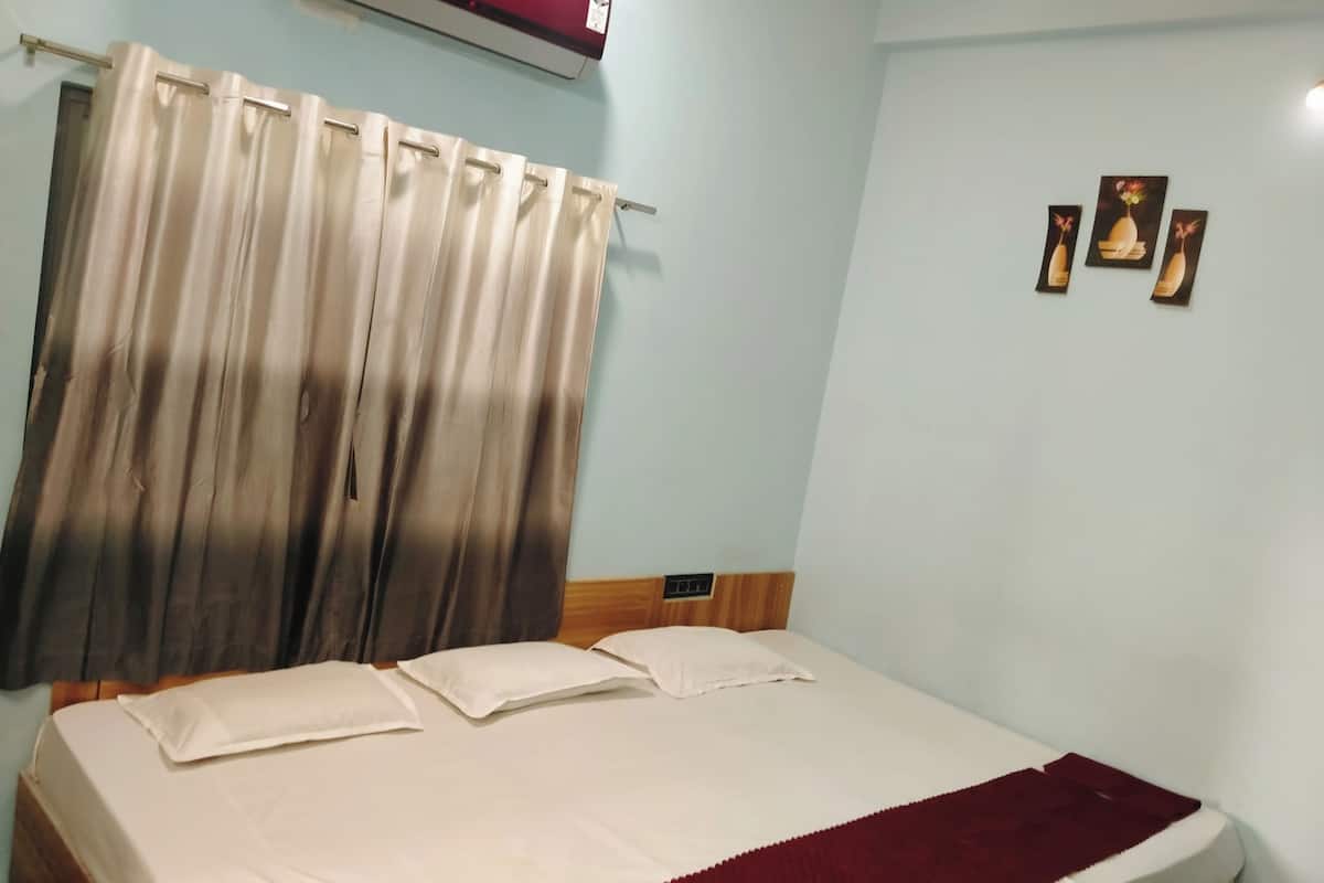 Une chambre à coucher avec un lit, des rideaux, un climatiseur et des œuvres d’art murales.