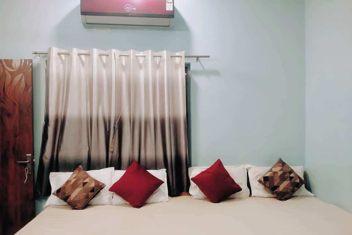 Une chambre à coucher avec un lit, des rideaux et un climatiseur fixé au mur.