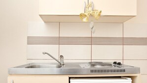 Een functionele keuken met een ingebouwd spoelbakje, een kleine koelkast en een decoratieve lamp.