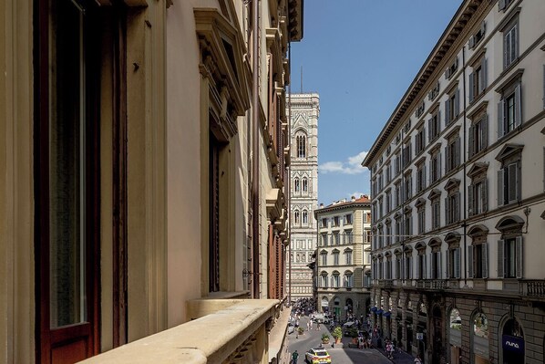 A street view with historic buildings, a prominent tower, and a busy pedestrian area.