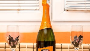 Una botella de Cinzano Prosecco D.O.C. sobre una mesa con dos copas que contienen trozos de chocolate.
