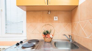 A kitchen with a gas stove, a sink, and a window with blinds.