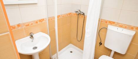 Un baño pequeño con lavamanos, inodoro y ducha.