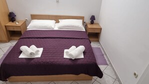 A neatly made bed with a purple bedspread and two rolled towels placed on the bed. - Apartments Pansion Franka 3* - Apartment 10 (Brist)