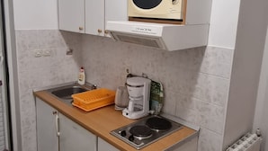 A compact kitchenette with a microwave, coffee maker, and a small stove. - Apartments Pansion Franka 3* - Apartment 10 (Brist)