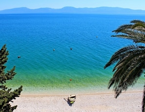 Enjoy a serene beach setting with a clear view of the sea and distant mountains, perfect for relaxation or water activities.