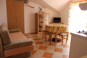 Cozy living space with a sofa, dining table for two, and a mounted TV.