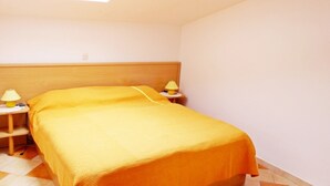 A room with a bed, two bedside tables with lamps, a skylight, and a tiled floor.