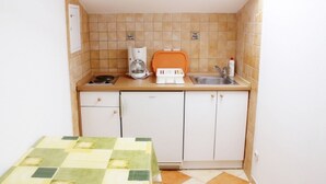 A compact kitchen with a stove, coffee maker, and sink.