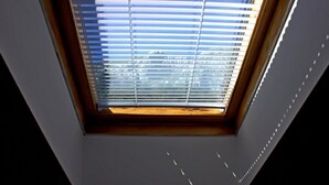 A skylight with horizontal blinds, a wooden frame, and a dark ceiling.