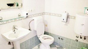 A bathroom with a sink, toilet, and hand dryer.