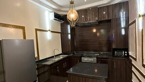 A modern kitchen with dark wood cabinets, a stainless steel refrigerator, a central island, and a pendant light. - Spacious 3-bedroom apartment in excellent Abuja with AC, WiFi, fitness room (Abuja)