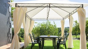 A covered patio area with a table and chairs, surrounded by white curtains.