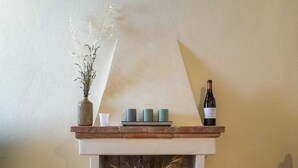 A fireplace with a wine bottle, candles, and a vase of flowers. - Tuscan Escape with pool and vineyard view - Gaiole in Chianti (Gaiole in Chianti)