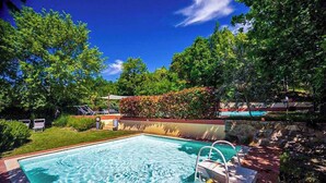 A rectangular swimming pool with a ladder, surrounded by a stone wall and lush greenery. - Tuscan Escape with pool and vineyard view - Gaiole in Chianti (Gaiole in Chianti)