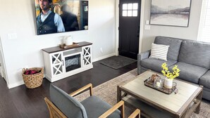 Un salon avec un téléviseur, un canapé, une table basse et une cheminée.