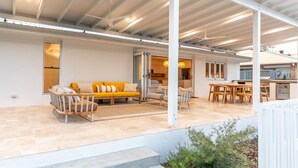 Una zona exterior moderna amb sofà, cadires i taula de menjador.