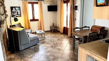 Una sala de estar acogedora con un sofá, una mesita y un comedor con sillas y una mesa de madera.