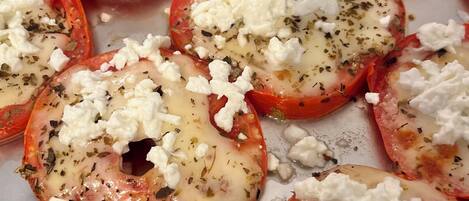 Una bandeja de tomates al horno cubiertos con queso y hierbas.