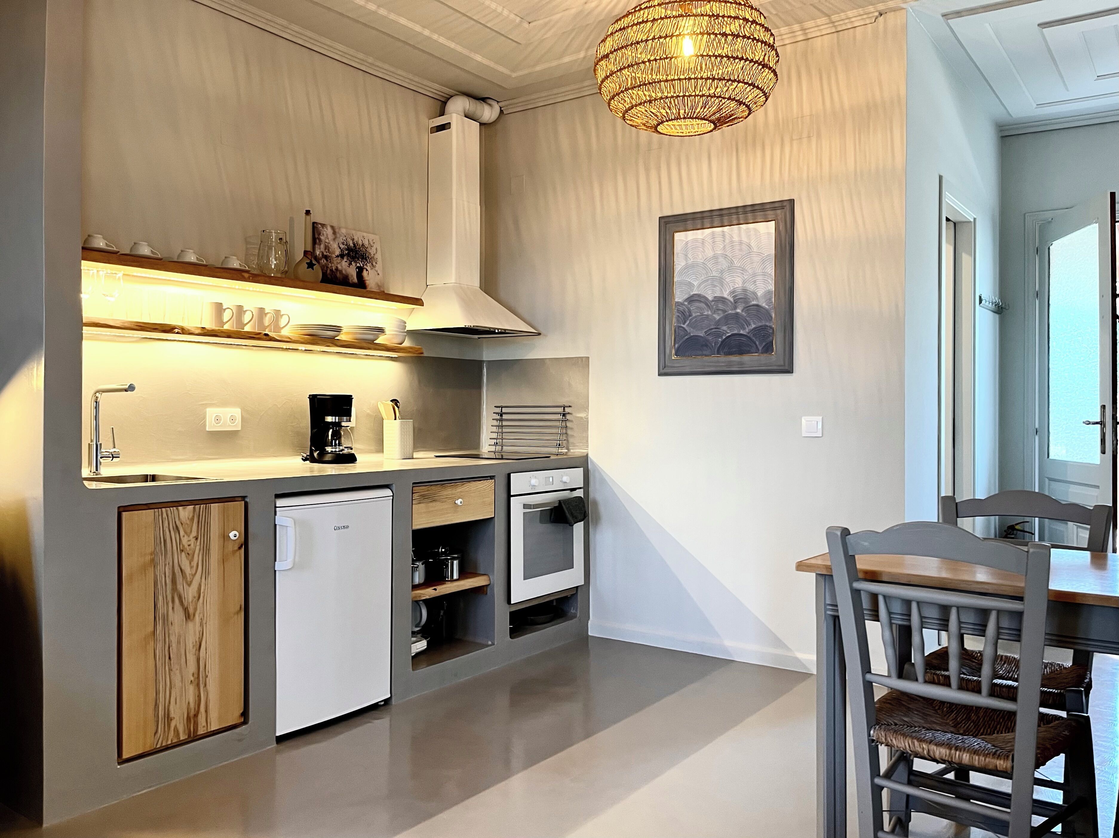 Une cuisine de taille réduite équipée d’un lave-vaisselle, d’une cuisinière et d’un luminaire suspendu.