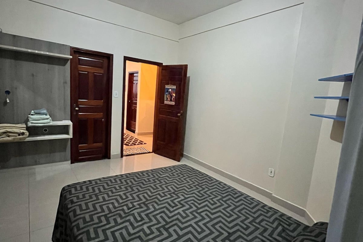 Une chambre à coucher comprenant un lit, une armoire et une porte donnant sur une autre pièce.