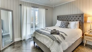A bedroom with a large bed, a ceiling fan, a nightstand, and a view through a glass door. - Tranquil Gantt Lake Home w/ Deck & Patio! (Andalusia)