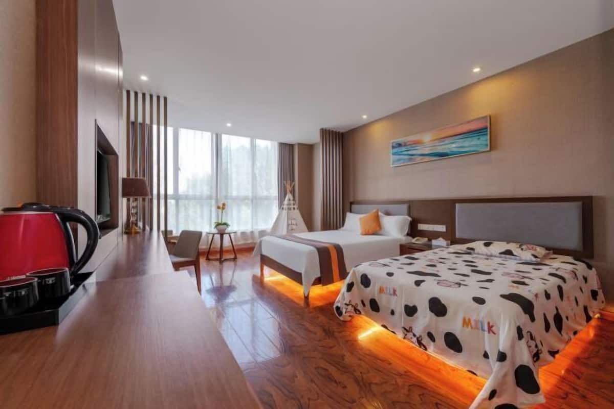 A modern hotel room with a large bed, bedside tables, a desk, and a view of the outdoors.