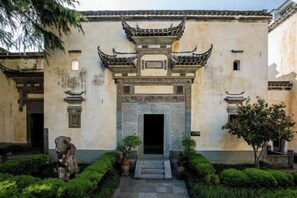 A traditional building with a central entrance, surrounded by well-maintained greenery and a stone statue. - Superior Hotel (Shexian Ancient City) (She County)