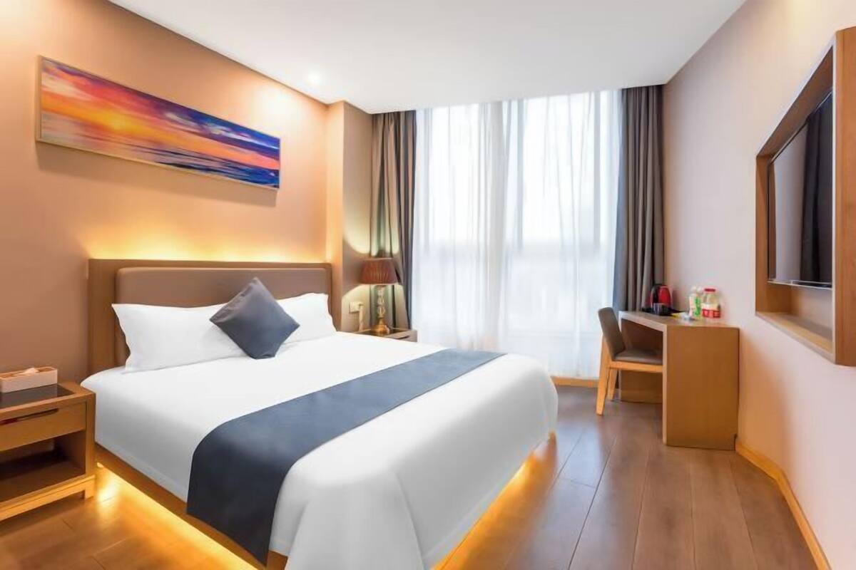 A modern hotel room with a large bed, a desk, and a TV.