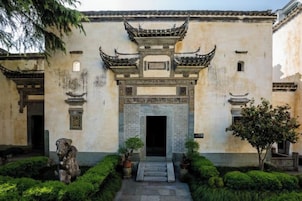 Un edificio tradicional con una entrada central, flanqueada por estatuas y plantas en macetas.