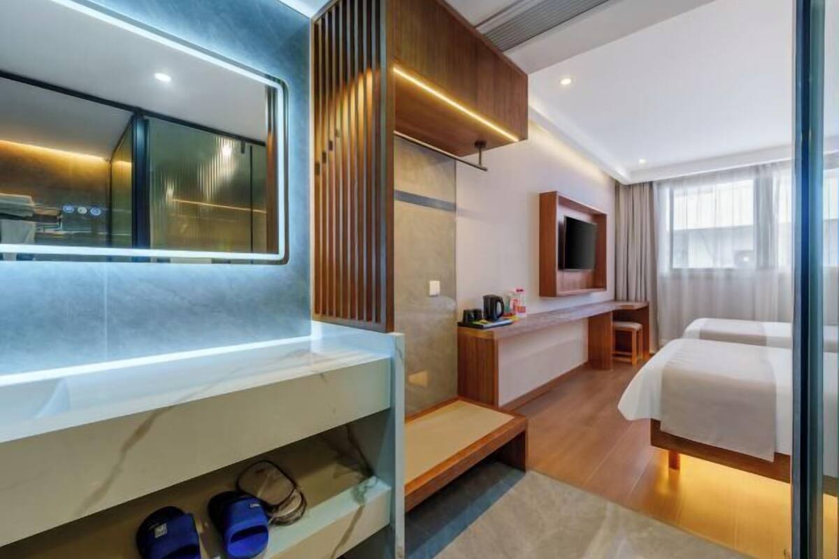 A hotel room with a bed, a TV, a desk, and a shower area.