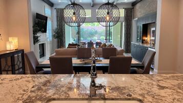 A modern kitchen with a marble countertop, a sink, and a dining area with a sofa and chairs.