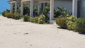 Een rij strandvilla's met een zandstrand en uitzicht op de oceaan.
