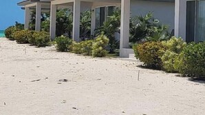 Une rangée de villas situées en bord de mer, avec une plage de sable et vue sur l’océan.