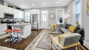 A modern kitchen with white cabinets, stainless steel appliances, and a central island with stools. - Bright Washington DC Apartment (Washington)