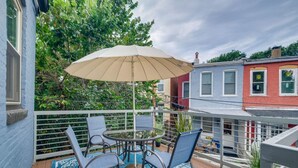 A patio with a round table and chairs, a beige umbrella, and a blue patterned rug. - Bright Washington DC Apartment (Washington)