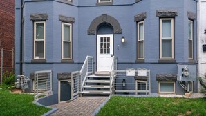 A multi-story building with a central white door, multiple windows, and a set of stairs leading to the entrance. - Bright Washington DC Apartment (Washington)