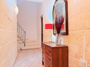 A hallway with a wooden dresser, a mirror, and a staircase.