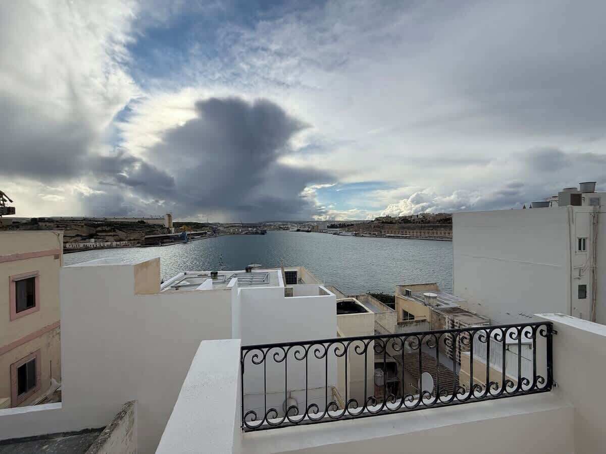 A balcony with a railing overlooking a body of water and buildings.