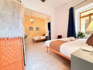 A hotel room with a bed, a desk, a chair, a lamp, and a window with curtains.