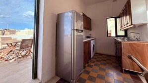 Eine kleine Küche mit Kühlschrank, Waschmaschine und Holzausstattung.
